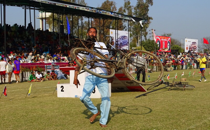 Man Lifting Cycle with Teeth at 79th Kila Raipur Sports Festival 2015 in Punjab, India